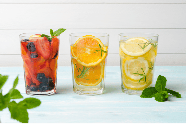 tres copos de agua com pedaços de frutas neles